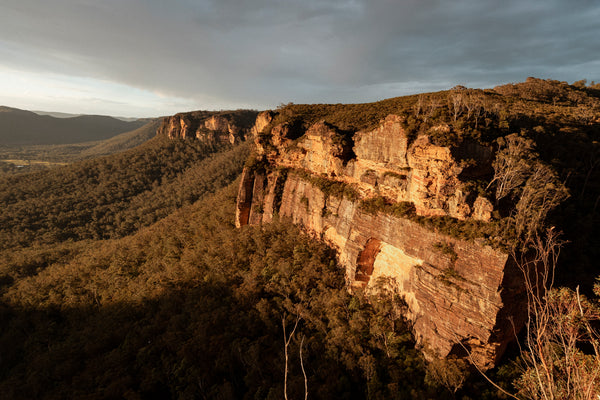 Landscape shot of the blue mountains in Australia, with the sun setting against the red rock.