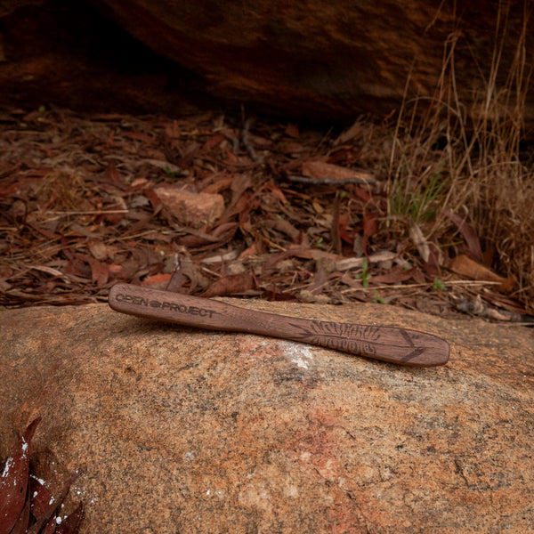 Wooden climbing brush with 'Open Project' branding on a rock with natural background
