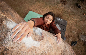 Female climbing a rock face with a focus on hand placement