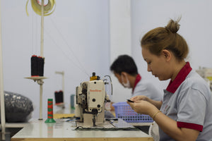 Person operating a sewing machine in an industrial setting