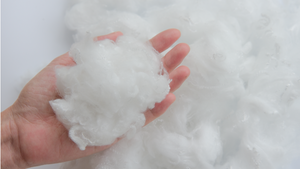 Hand holding a ball of recycled polyester against a white background
