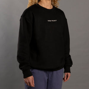 Woman wearing a black sweatshirt with 'OPEN PROJECT' text on a gray background