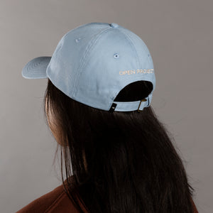 Person wearing a light blue cap with 'OPEN PROJECT' text on a gray background