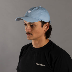Man wearing a light blue cap and black shirt with 'Open Project' logo on a gray background