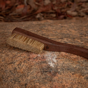 Brown brush with bristles on a textured stone surface