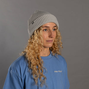 Woman wearing grey open project beanie with blue t shirt