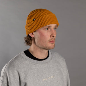 Man wearing a mustard yellow beanie and gray sweatshirt with 'Open Project' logo on a gray background