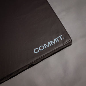 Black crash pad with 'COMMIT.' branding on a gray background