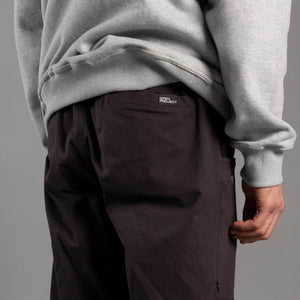Person wearing a gray sweatshirt and dark pants with a brand logo on a gray background