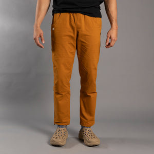 Person wearing mustard yellow climbing pants on a gray background