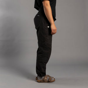 Person wearing black climbing pants and sandals on a gray background