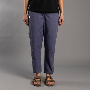 Person wearing purple climbing pants and brown sandals on a gray background