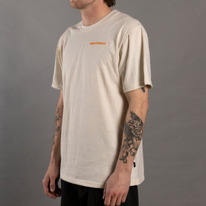 Person wearing a beige t-shirt with a logo on a gray background