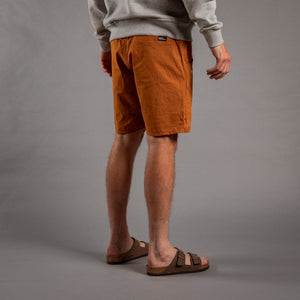 Person wearing brown shorts and gray sweatshirt on a gray background