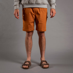 Person wearing brown shorts and sandals on a gray background