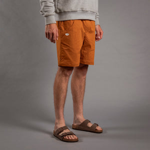 Person wearing brown shorts and sandals on a gray background