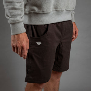 Person wearing a gray sweatshirt and black shorts with a logo on a gray background