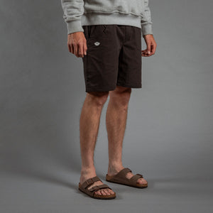 Person wearing dark shorts and sandals on a gray background
