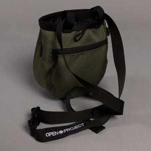 Green chalk bag with black strap on a gray background